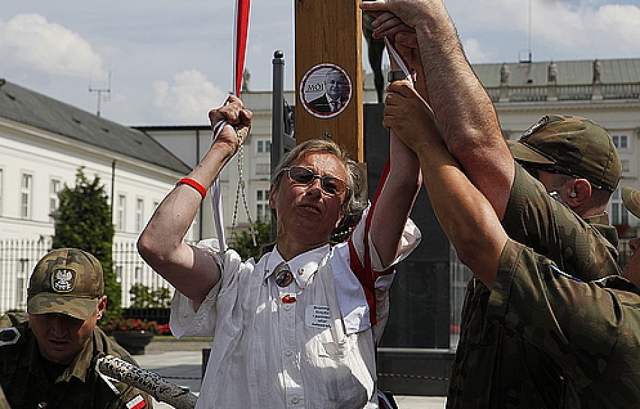 Kobieta trzyma się biało-czerwonej szarfy zawieszonej na harcerskim krzyżu (fot. PAP/Grzegorz Jakubowski )